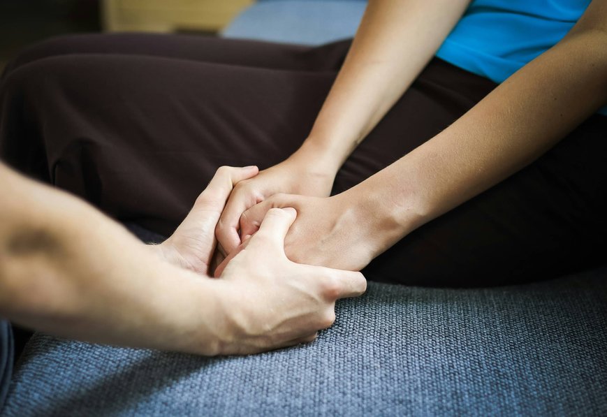 Terapeut držící klienta za ruce